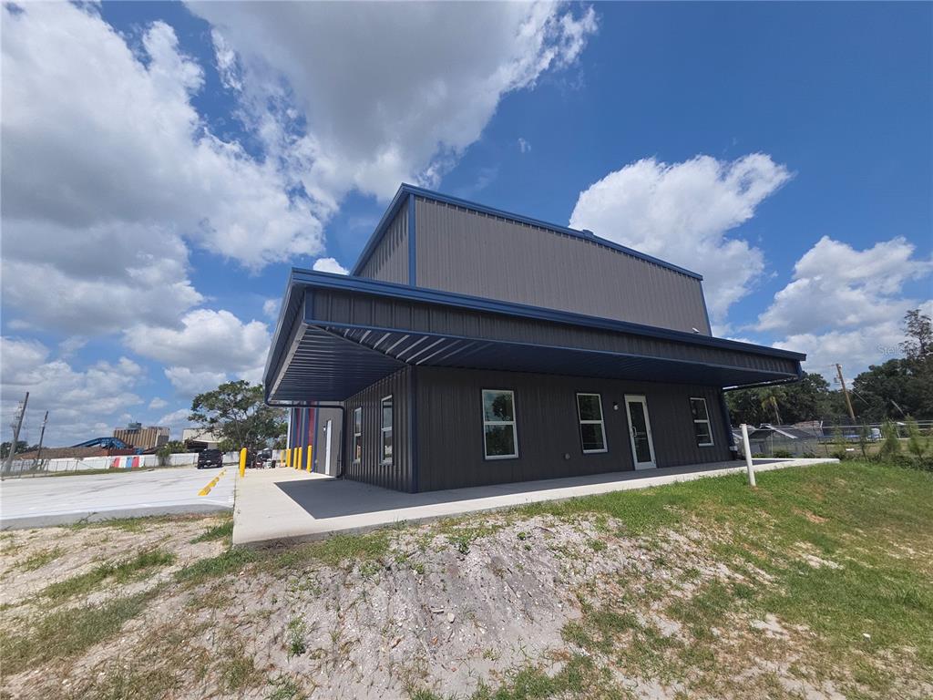 A modern, dark-sided metal commercial building with a wrap-around porch under a blue sky — 2173 SW HIGHWAY 17, ARCADIA, FL