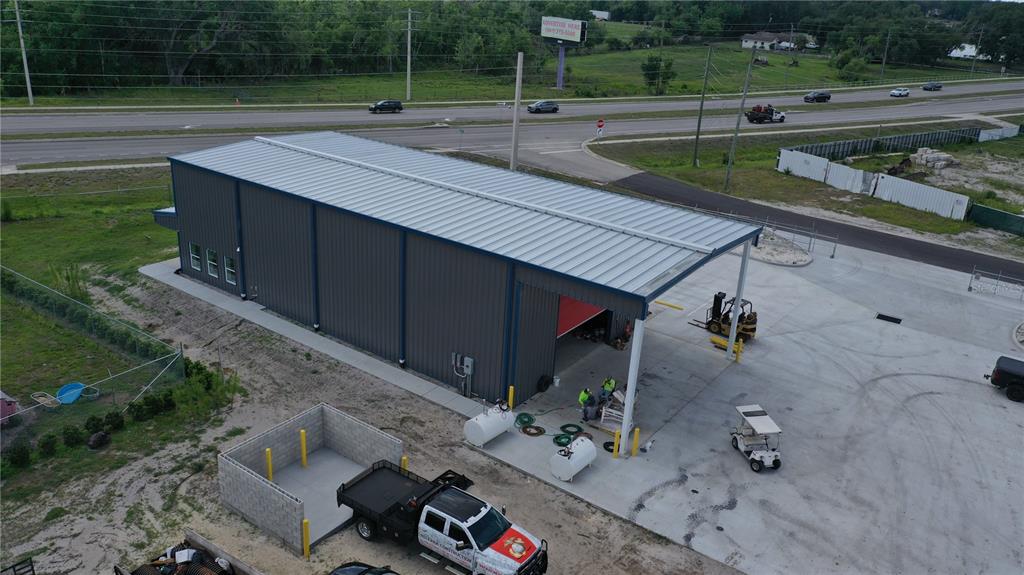 An aerial view shows a metal industrial building with a covered bay and adjacent parking — 2173 SW HIGHWAY 17, ARCADIA, FL