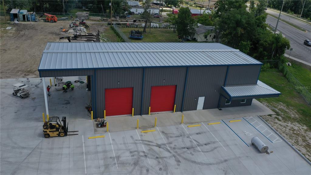 An aerial view shows a metal warehouse building with two red roll-up doors and parking — 2173 SW HIGHWAY 17, ARCADIA, FL
