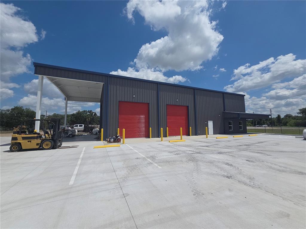 A modern metal warehouse building features two red roll-up doors and a covered loading area — 2173 SW HIGHWAY 17, ARCADIA, FL