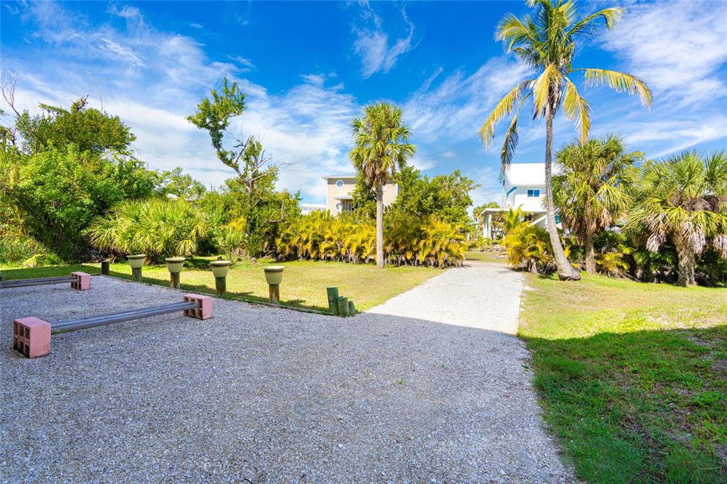 A gravel driveway leads toward a house surrounded by palm trees and lush tropical landscaping — 9542 RUM RUNNER ROAD, PLACIDA, FL