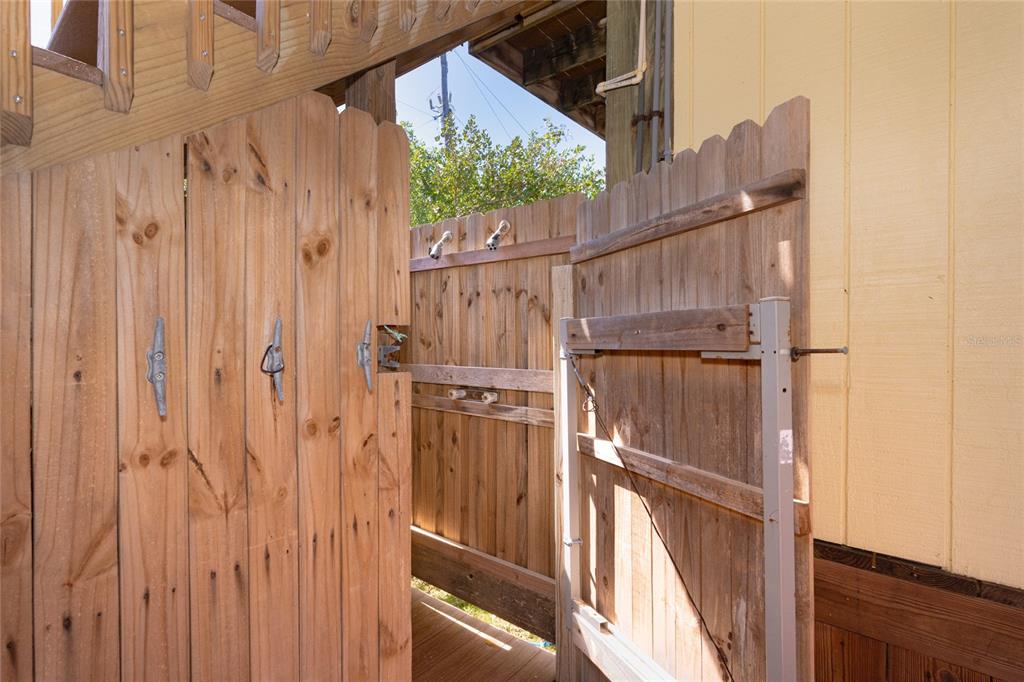 An outdoor shower area features wooden privacy fencing and a gate beneath a staircase — 9542 RUM RUNNER ROAD, PLACIDA, FL