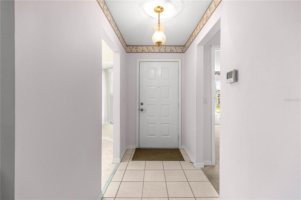 A tiled entryway features a white front door, a pendant light, and floral wallpaper trim — 6201 SW 84TH PLACE, OCALA, FL