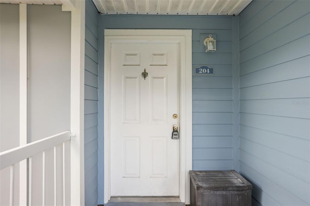 An open-concept living area features light tile flooring, a kitchen pass-through, and a glass door — 2584 GRASSY POINT DRIVE UNIT 204, LAKE MARY, FL