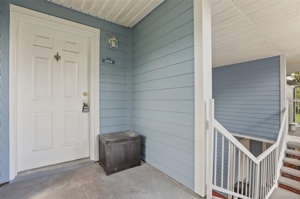 A kitchen features honey-oak cabinets, granite countertops, black appliances, and light-colored tile flooring — 2584 GRASSY POINT DRIVE UNIT 204, LAKE MARY, FL