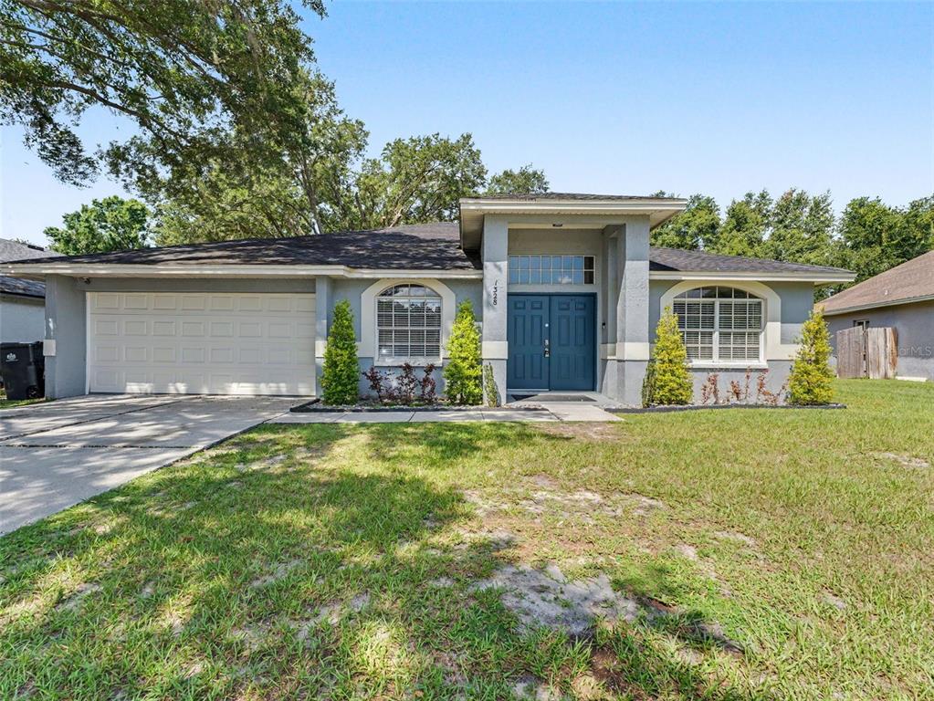A single-story house with a blue front door, arched windows, and a two-car garage — 1328 GANGPLANK DRIVE, VALRICO, FL