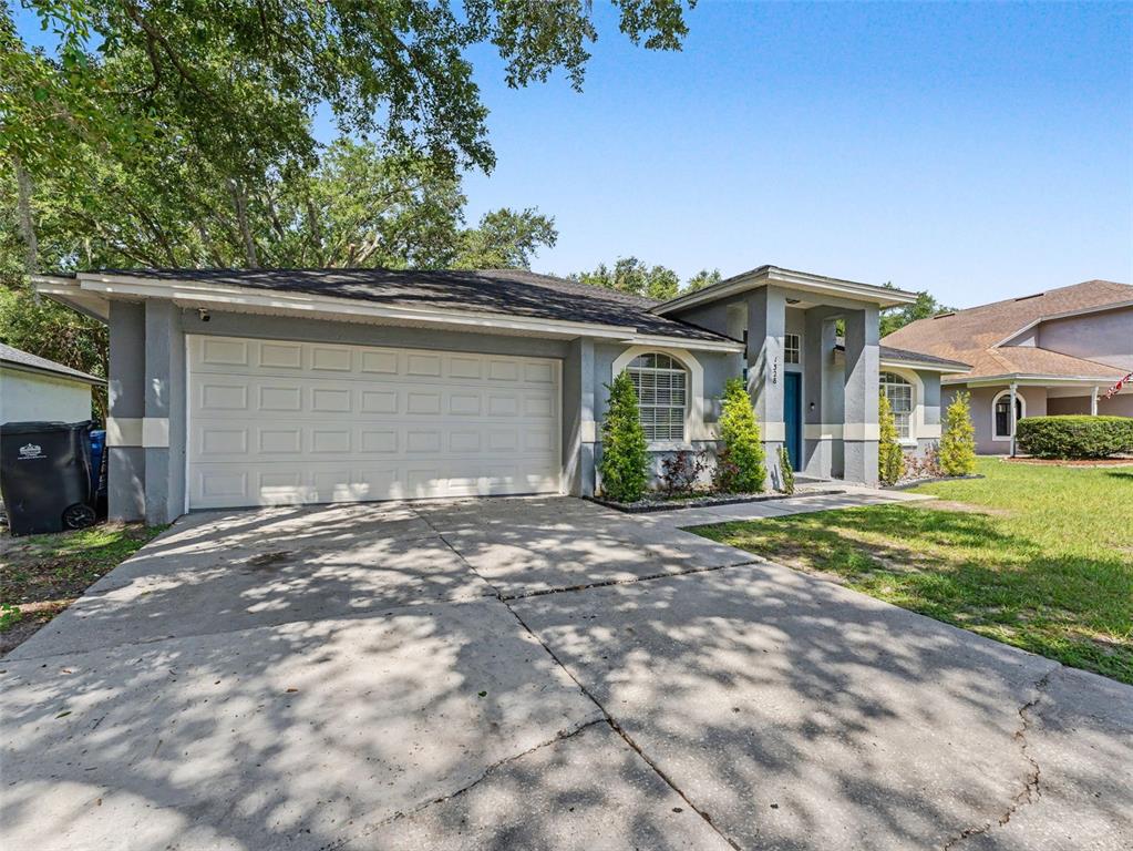 A single-story house with a blue front door, arched windows, and a two-car garage — 1328 GANGPLANK DRIVE, VALRICO, FL