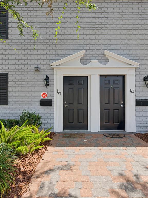 Two black front doors with white trim are set into a gray brick exterior wall — 193 LEWFIELD CIRCLE, WINTER PARK, FL
