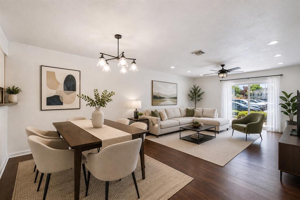 A spacious living room features dark wood-look flooring, a chandelier, and a sliding glass door — 193 LEWFIELD CIRCLE, WINTER PARK, FL
