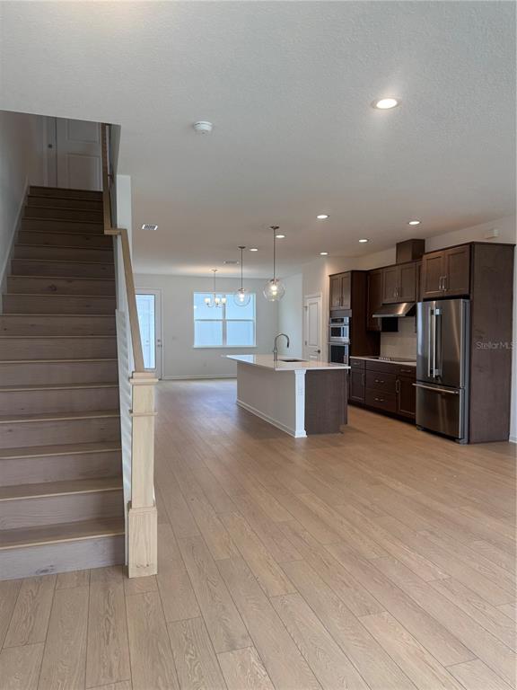 An open-concept kitchen and living area features dark wood cabinets, a central island, and stairs — 1868 CROWNCREST DRIVE, APOPKA, FL