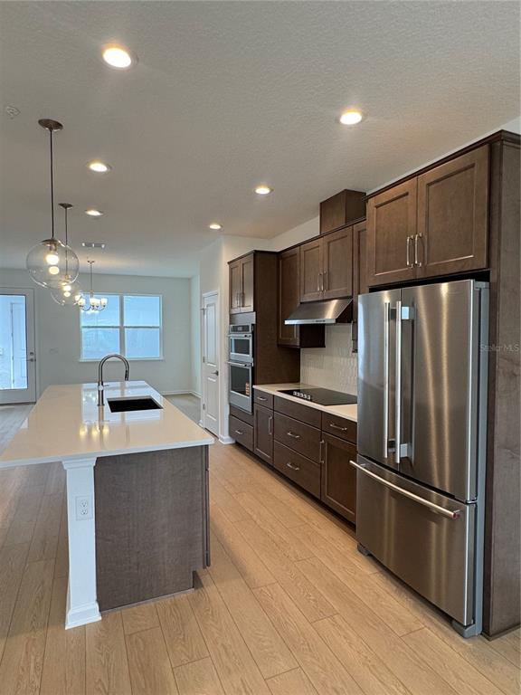 A modern kitchen features dark wood cabinets, stainless steel appliances, and a white island countertop — 1868 CROWNCREST DRIVE, APOPKA, FL