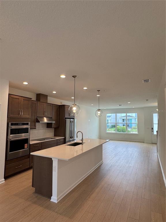 A modern kitchen features dark wood cabinets, a central island, and light wood-look flooring — 1868 CROWNCREST DRIVE, APOPKA, FL
