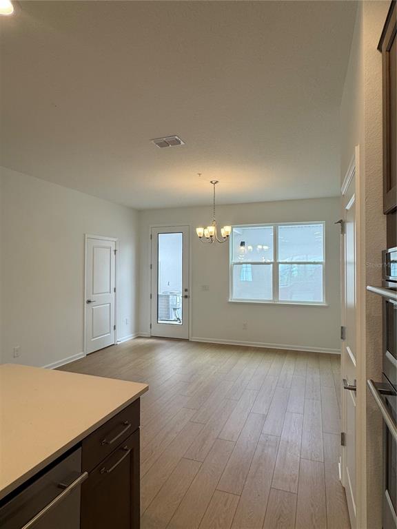 A kitchen and dining area features light wood-look tile flooring and a modern chandelier — 1868 CROWNCREST DRIVE, APOPKA, FL
