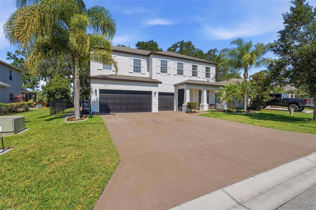 A two-story house with a light-colored exterior, a three-car garage, and palm trees — 8809 49TH AVENUE E, PALMETTO, FL