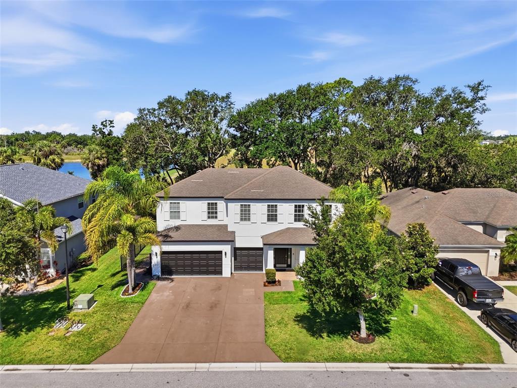 An aerial view of a two-story suburban house with a driveway and surrounding trees — 8809 49TH AVENUE E, PALMETTO, FL