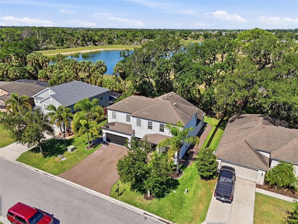An aerial view shows a two-story suburban house with a driveway and a nearby lake — 8809 49TH AVENUE E, PALMETTO, FL