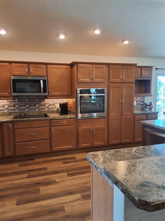 A kitchen features wood cabinets, stainless steel appliances, and a granite-topped island — 3526 CLUSTER COURT, THE VILLAGES, FL
