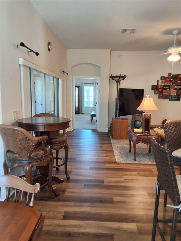 A living area with wood-look flooring, a high-top table, and a hallway leading to another room — 3526 CLUSTER COURT, THE VILLAGES, FL