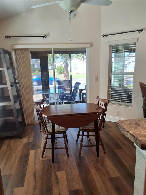A dining area features a drop-leaf table, wood-look flooring, and sliding glass doors to a patio — 3526 CLUSTER COURT, THE VILLAGES, FL