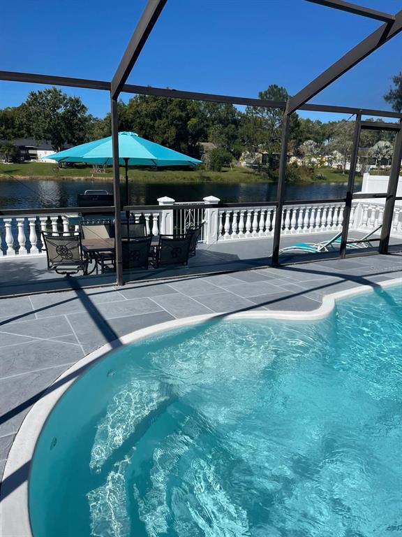 A swimming pool sits on a patio with a dining set and a lake view — 6423 MONTEREY BOULEVARD, TAMPA, FL