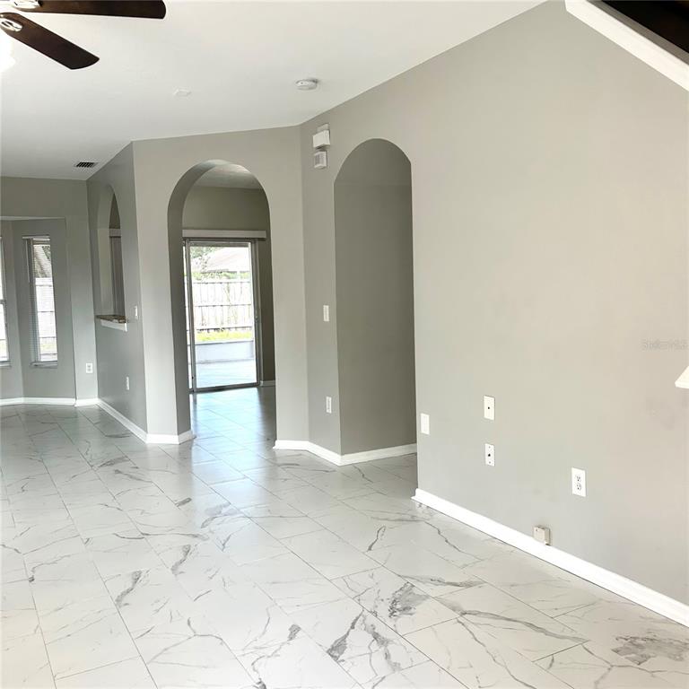 A bright, empty room features light-colored walls, a ceiling fan, and white marble-look flooring — 504 MAPLE POINTE DRIVE, SEFFNER, FL