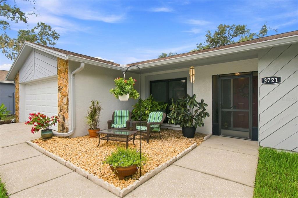 A single-story house features a light gray exterior, stone accents, a garage, and a lawn — 3721 SAND PEBBLE DRIVE, VALRICO, FL