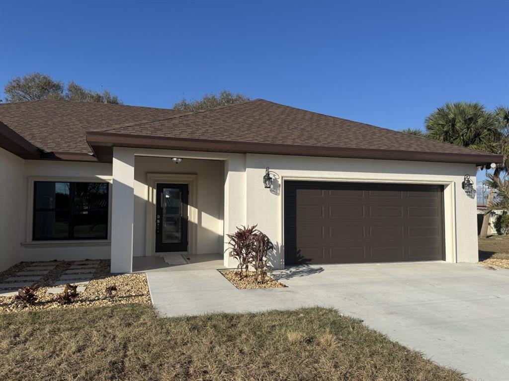 A single-story house with a white stucco exterior, brown roof, and a two-car garage — 2383 SW 2ND COURT, OKEECHOBEE, FL