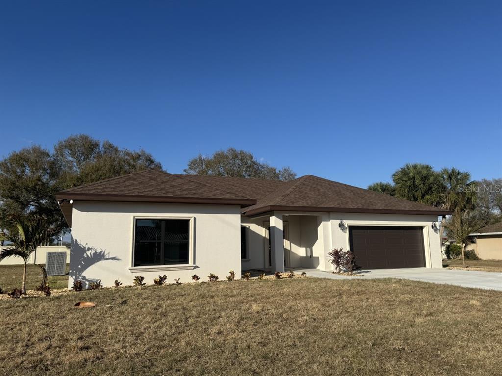 A single-story house with a white stucco exterior, brown roof, and a two-car garage — 2383 SW 2ND COURT, OKEECHOBEE, FL
