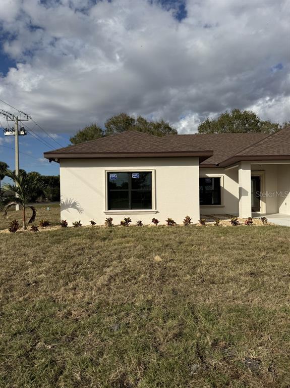 A single-story house with beige stucco walls, a brown roof, and a small palm tree — 2383 SW 2ND COURT, OKEECHOBEE, FL