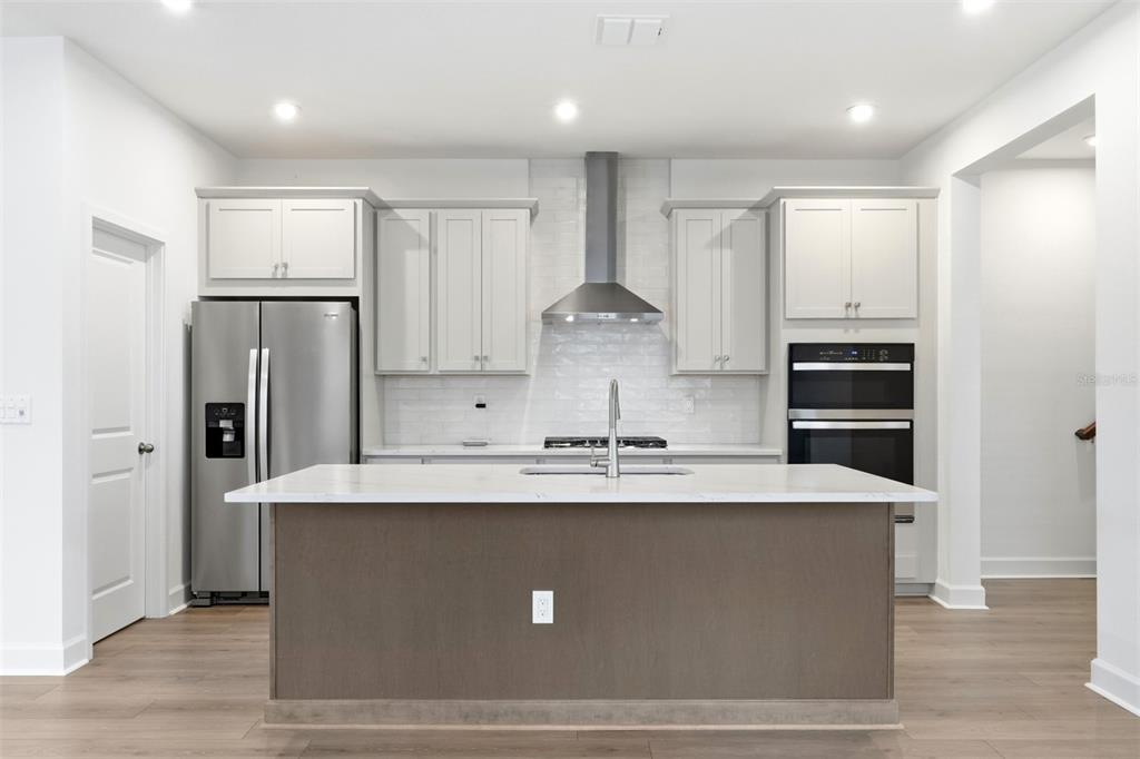 A modern kitchen features light gray cabinetry, stainless steel appliances, and a central island — 1901 SEAWALL WAY, CELEBRATION, FL