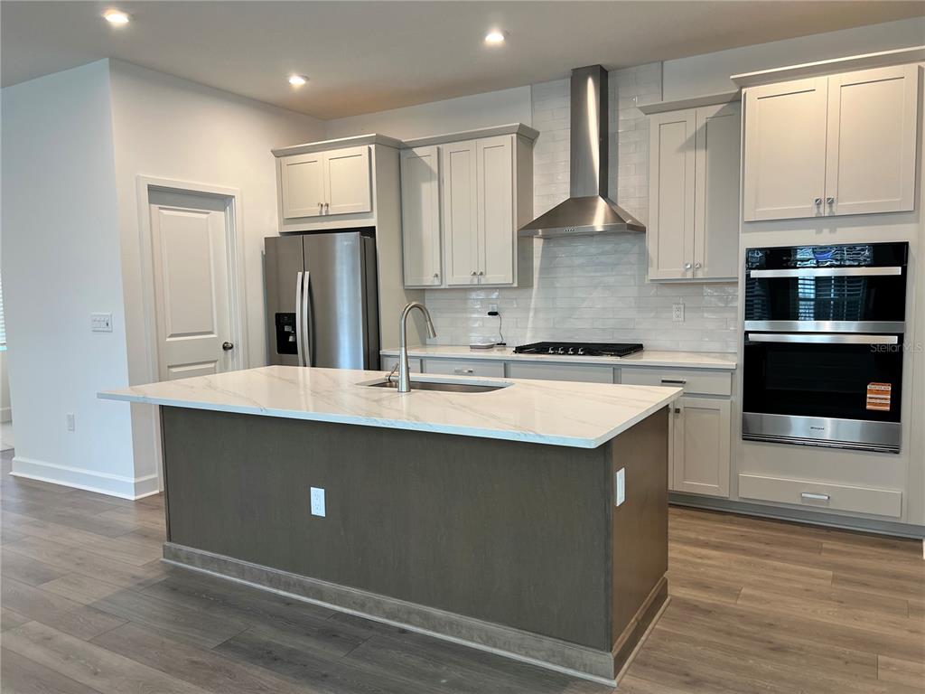 A modern kitchen features a large island with a white countertop and dark wood cabinetry — 1901 SEAWALL WAY, CELEBRATION, FL