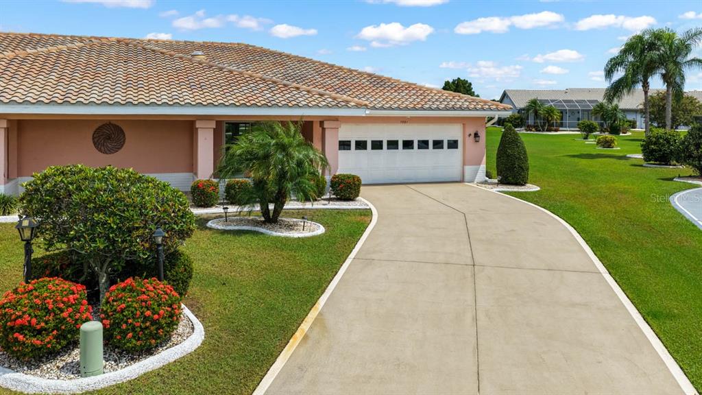 A single-story house with a tiled roof, a white garage door, and a concrete driveway — 1001 ARDMORE WAY, SUN CITY CENTER, FL