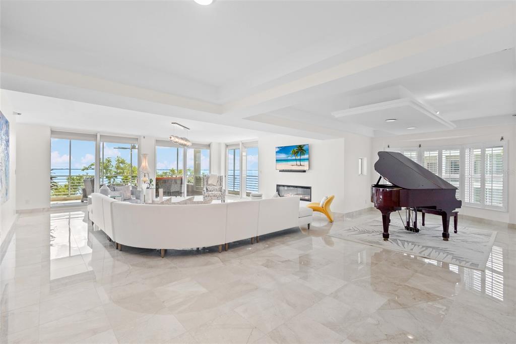 A spacious, white-walled living room features a large sectional sofa, grand piano, and balcony views — 2450 HARBOURSIDE DRIVE UNIT 244, LONGBOAT KEY, FL