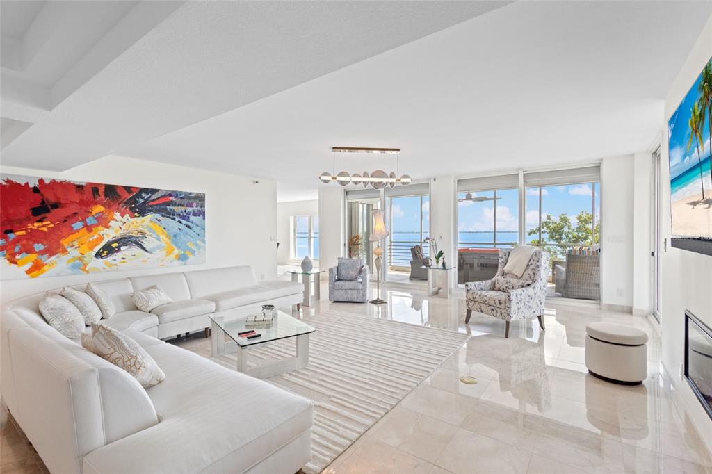 A bright living room features a white sectional sofa, patterned armchairs, and floor-to-ceiling windows — 2450 HARBOURSIDE DRIVE UNIT 244, LONGBOAT KEY, FL