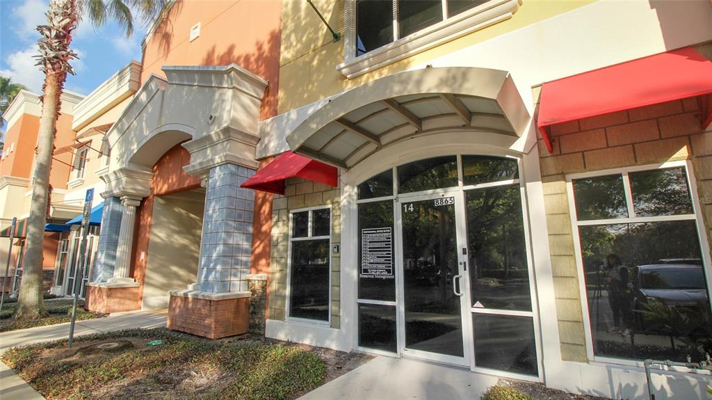 The exterior of a commercial building features glass storefront doors, red awnings, and brick accents — 8865 COMMODITY CIRCLE UNIT 109, ORLANDO, FL