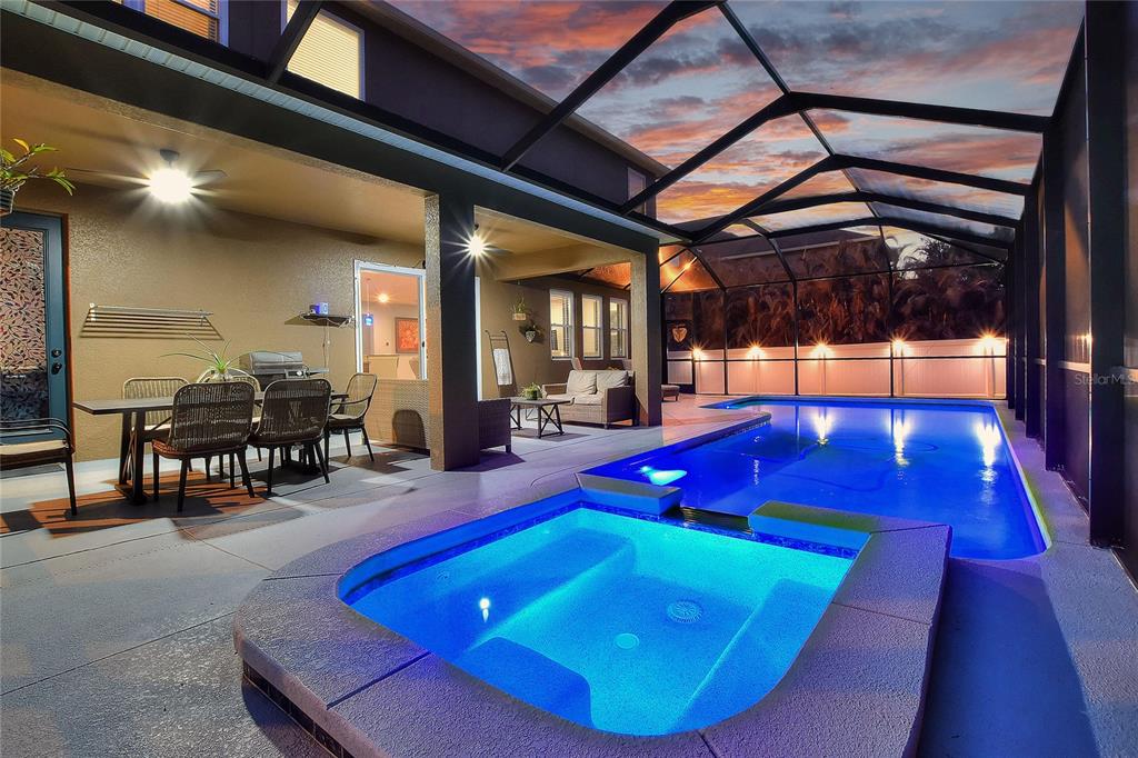 An open-concept living room features gray leather furniture, tile flooring, and an adjacent kitchen — 232 MAGNETA LOOP, AUBURNDALE, FL