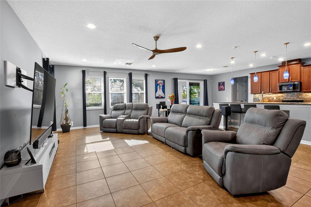 A kitchen features wood cabinets, granite countertops, a central island with stools, and pendant lighting — 232 MAGNETA LOOP, AUBURNDALE, FL