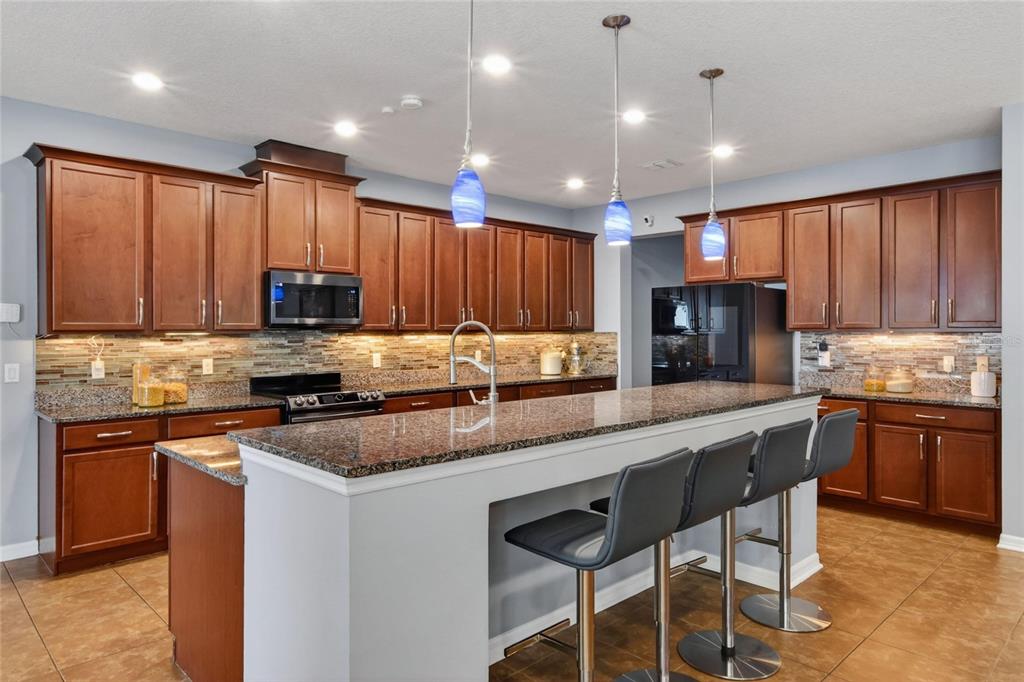 A kitchen features dark wood cabinets, granite countertops, a breakfast bar, and a sliding glass door — 232 MAGNETA LOOP, AUBURNDALE, FL