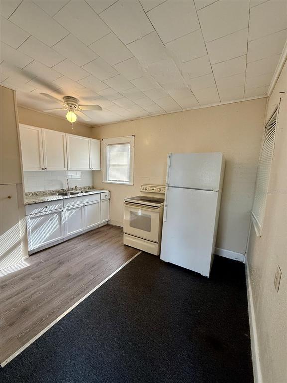 A kitchen with white cabinets, a white stove, a white refrigerator, and two-toned flooring — 634 14TH STREET N UNIT 1/2, ST PETERSBURG, FL