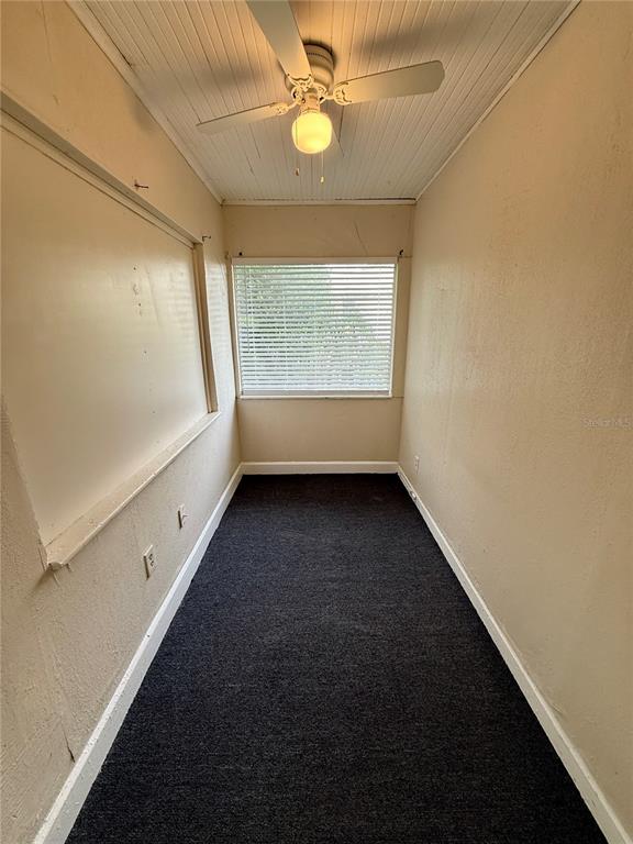 A narrow room features dark carpeting, beige walls, a ceiling fan, and a window with blinds — 634 14TH STREET N UNIT 1/2, ST PETERSBURG, FL