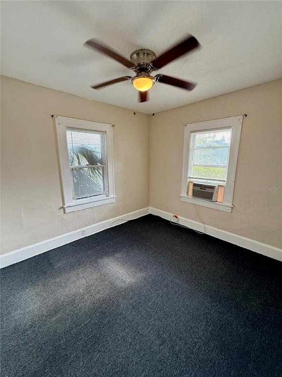 An empty bedroom with beige walls, dark carpeting, a ceiling fan, and two windows — 634 14TH STREET N UNIT 1/2, ST PETERSBURG, FL