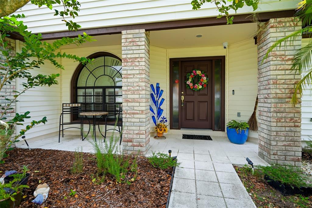 The front entrance features a brown door, brick columns, and a small patio seating area — 1150 WINDSOR WAY, LUTZ, FL