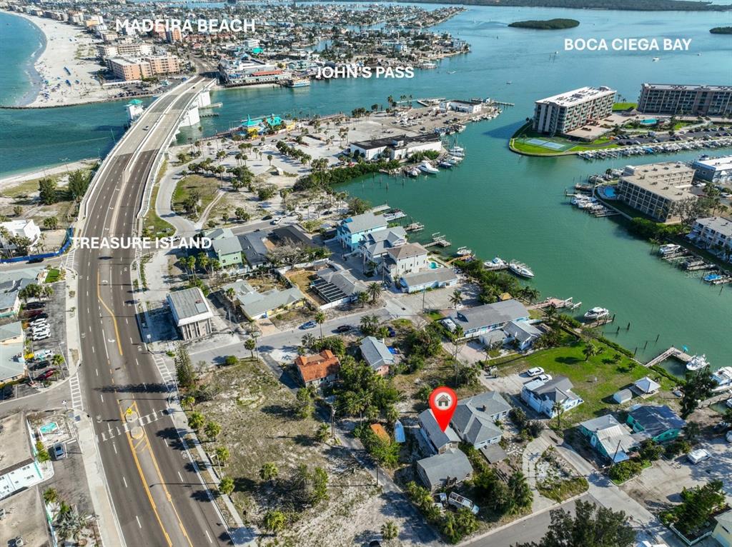 An aerial view shows two houses, a storage container, and a boat near a bridge — 108 125TH AVENUE, TREASURE ISLAND, FL