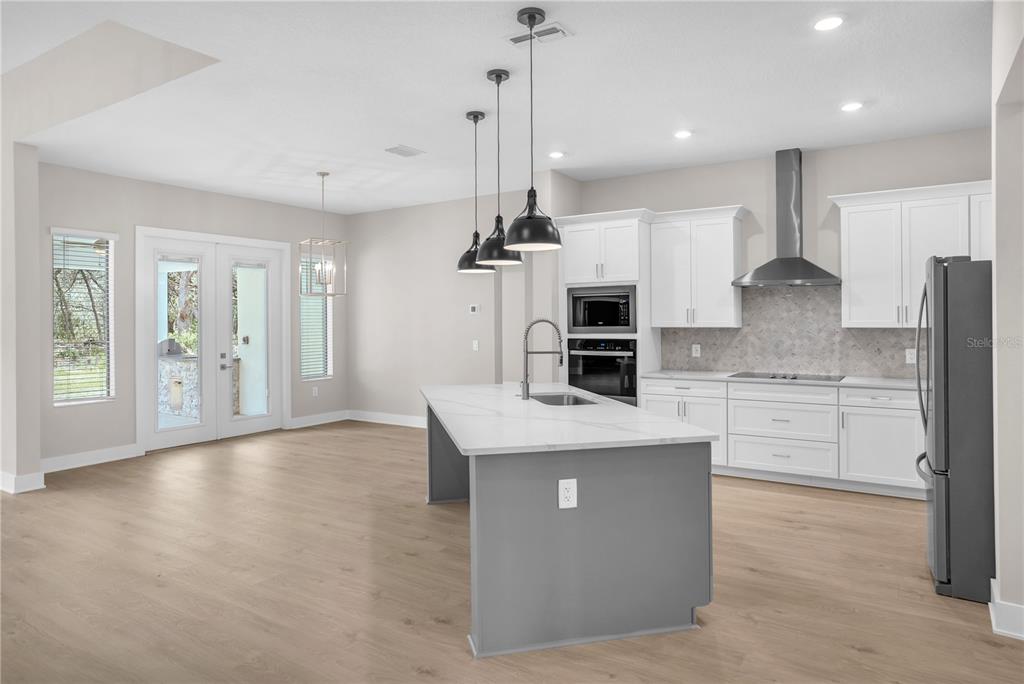 An entryway features light wood flooring, a carpeted staircase with wooden railings, and a modern chandelier — 13510 HAFLINGER WAY, HUDSON, FL