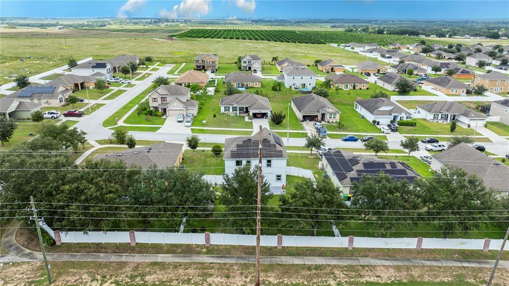 An aerial view shows a suburban neighborhood with houses, streets, and a white perimeter fence — 2015 BARSTOW LANE, DUNDEE, FL