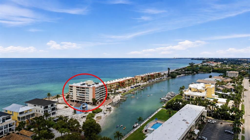 An aerial view shows a coastal residential area with multi-story apartment buildings and houses — 9150 BLIND PASS ROAD UNIT 206, SARASOTA, FL