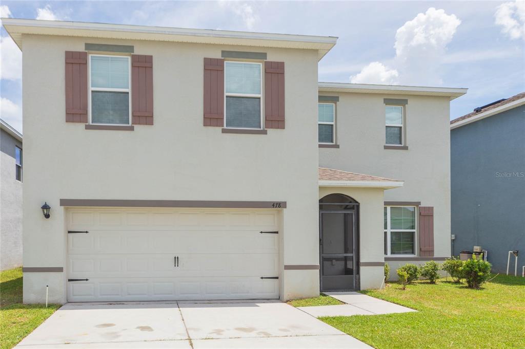 A two-story house with a beige stucco exterior, a two-car garage, and a front entryway — 478 AUTUMN STREAM DRIVE, AUBURNDALE, FL
