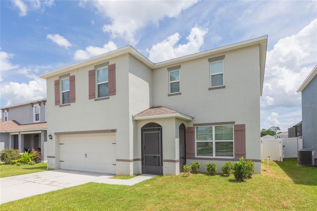 A two-story suburban house with a beige stucco exterior, brown shutters, and a two-car garage — 478 AUTUMN STREAM DRIVE, AUBURNDALE, FL