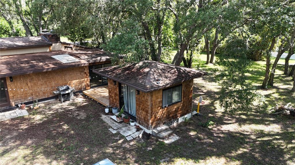 An aerial view shows a shingled detached structure and a main house with wooden siding — 34146 UMBRELLA ROCK DRIVE, WEBSTER, FL