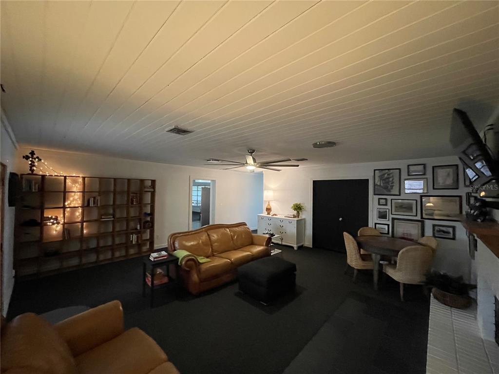 A living room features a tan leather sofa, a dark rug, and a large bookshelf — 879 S TERRACE DRIVE, EAGLE LAKE, FL